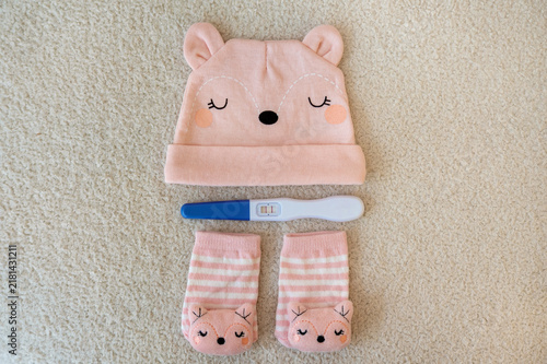 Foto Positive pregnancy test with baby hat and socks on a soft beige background