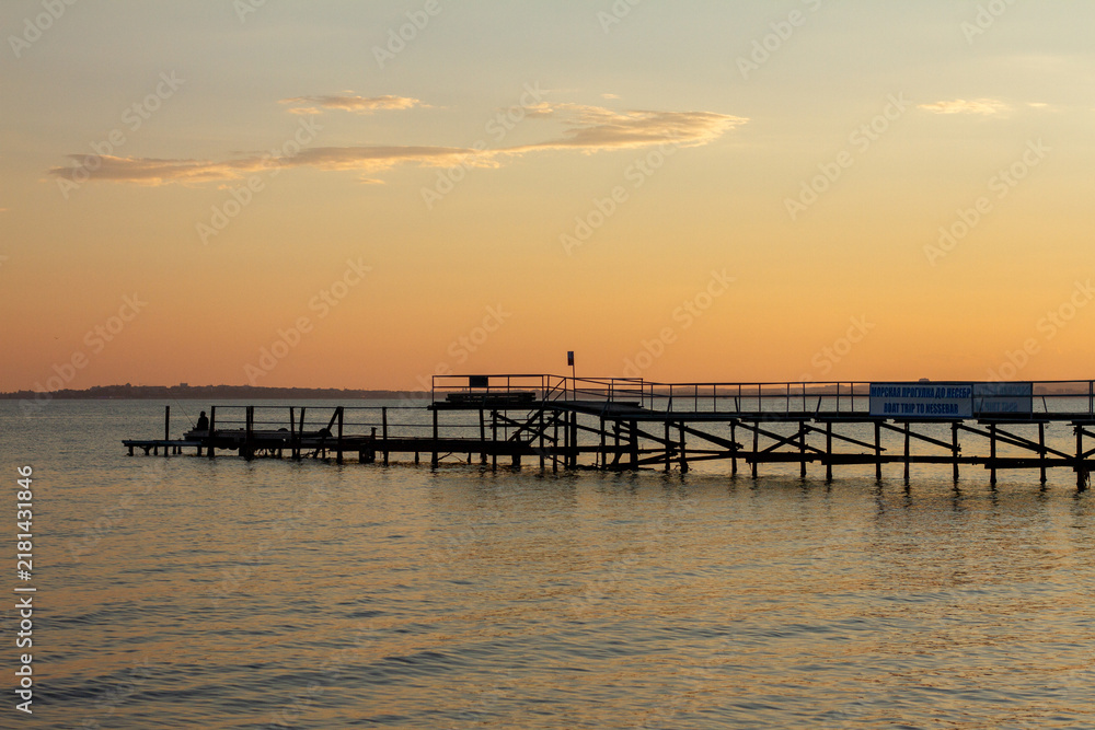 Obraz premium Wooden Pier extending into Sea at Sunset Sky
