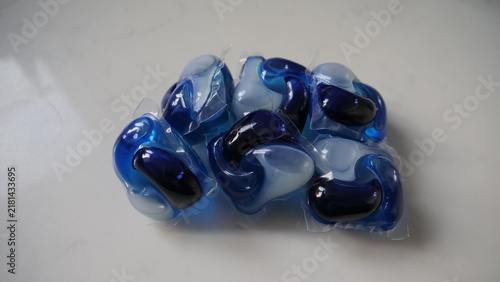 Cuadro en lienzo Pile of blue and clear laundry detergent pods on a white surface