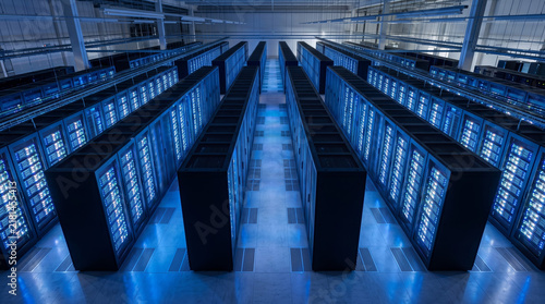 Aerial perspective of a pristine data center floor featuring long rows of glowing server cabinets. Cool white and blue ambient lighting creates a clean, minimalist industrial design aesthetic.