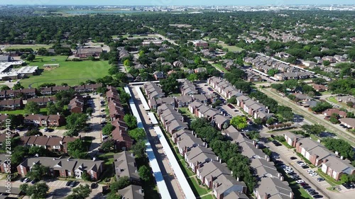 Sprawling apartment complexes border Parkway Boulevard near Mockingbird Elementary School. Lengthy covered carports, parked automobiles, lush green residential parks border Coppell, Texas.
