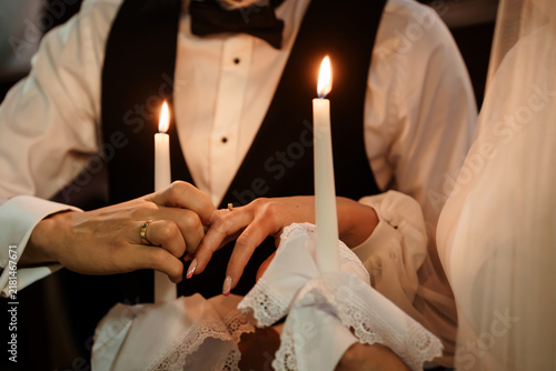 Cuadro en lienzo Groom placing a wedding ring on a bride finger during a traditional candlelit ce