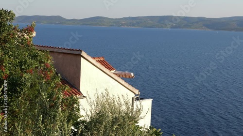 Mediterranean coastline view with house roof overlooking calm blue sea