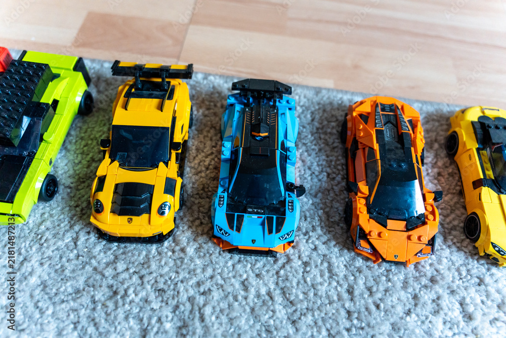 Obraz premium Warsaw, Poland - Sep 4, 2026: Row of four LEGO Technic model cars in green, yellow, blue and orange on a gray rug
