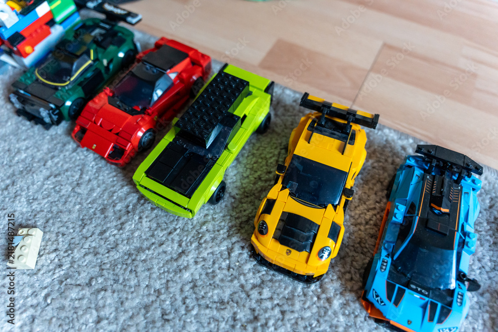 Obraz premium Warsaw, Poland - Sep 4, 2026: Row of LEGO Technic model cars in green, red, yellow and blue on a gray rug