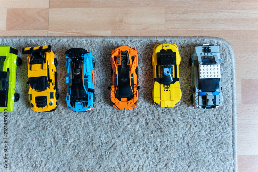 Obraz premium Warsaw, Poland - Sep 4, 2026: Row of seven LEGO Technic model cars lined up on a gray carpet near a wooden floor