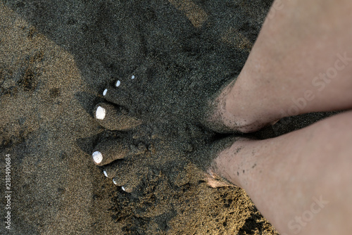 Foto A person stands barefoot on wet dark volcanic sand along a tropical beach in Costa Rica