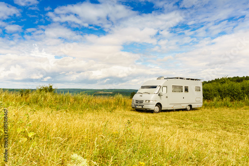 Camping car parked in a field with blue sky during daytime in a rural area
