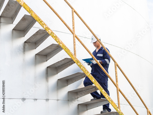 Engineers petrochemical are using digital tablets for technical inspections in oil refinery. Technicians working on checklist in the oil storage tank area. Factory and industry manufacturing. Oil tank