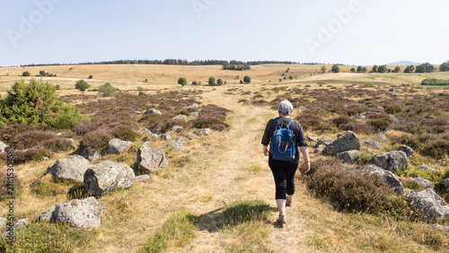 Fotografie femme avec sac à dos en train de randonner sur les estives sauvages du plateau d