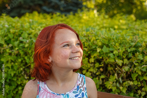 A portrait of a teenage girl, smiling and enjoying a sunny summer day.