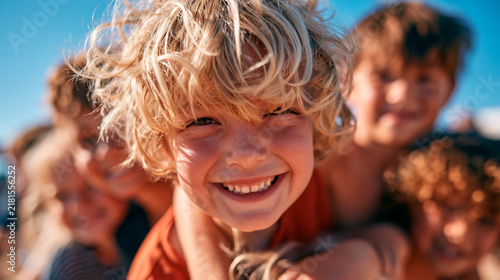 Close-up portrait of a joyful smiling child with messy blonde curly hair outdoors