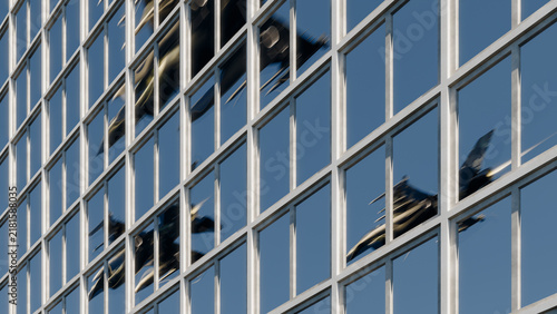 Quadro su tela Fighter jet reflection in modern glass skyscraper windows
