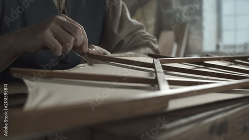 Foto Hands of a medieval craftsman sewing a fabric hem on a wing model with a needle