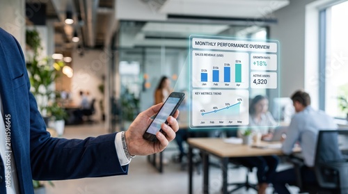 Businessman holding smartphone with futuristic hologram interface showing monthly performance overview, sales revenue charts and growth rate statistics, augmented reality