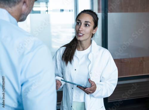 Female doctor with tablet advising male patient at medical practice