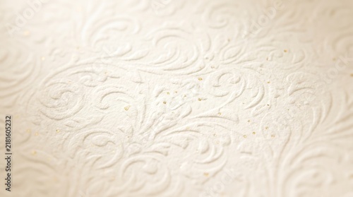 Elegant white paper texture featuring intricate embossed floral patterns and subtle golden metallic dust accents under soft bright studio lighting