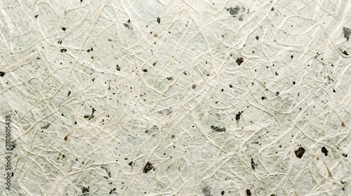 Handmade paper texture featuring natural organic plant fibers and dark brown inclusions embedded within an off white rustic recycled surface