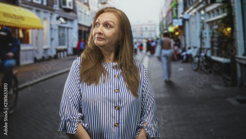 Konstfotografi Woman with visible face looking to the right on a cobbled street wearing striped blouse; curiosity memory