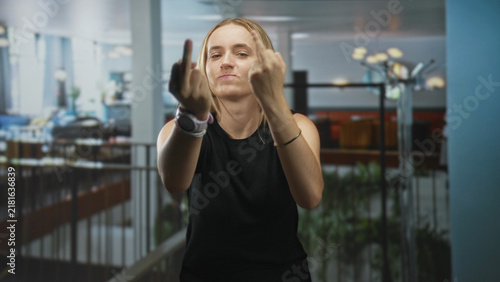 Quadro su tela Woman showing middle finger with smartwatch and bracelet visible in building; defiance bold attitude