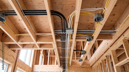 New Residential Construction Site Showing Electrical Wiring, Conduits, and Junction Boxes Installed in Wooden Ceiling Joists and Framework.