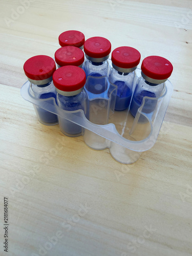 GHK-Cu, copper tripeptide in a vial and bacteriostatic water on a wooden background.