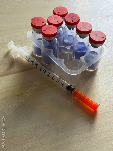 GHK-Cu, copper tripeptide in a vial and bacteriostatic water on a wooden background.