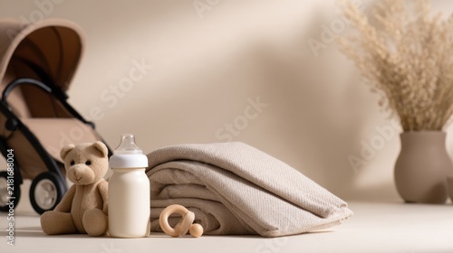 A soft beige scene featuring a teddy bear, a baby bottle, folded blankets, and decorative elements