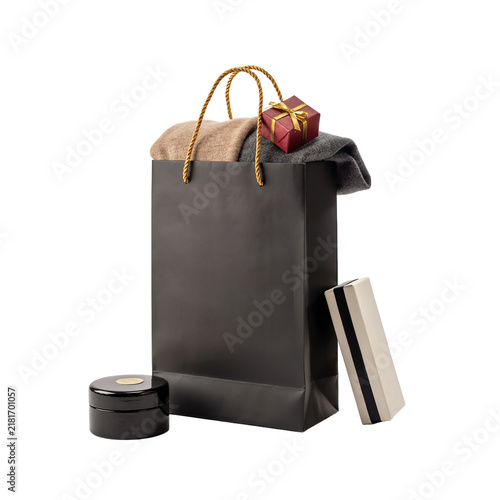 Black shopping bag filled with fashion items and accessories, accompanied by a small gift box and a cosmetic jar.