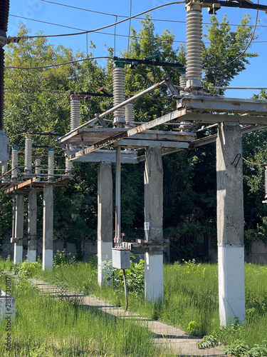 Foto High voltage industrial power transformer unit equipped with cooling pipes, high voltage bushings, and conservator tank installed at an electrical substation