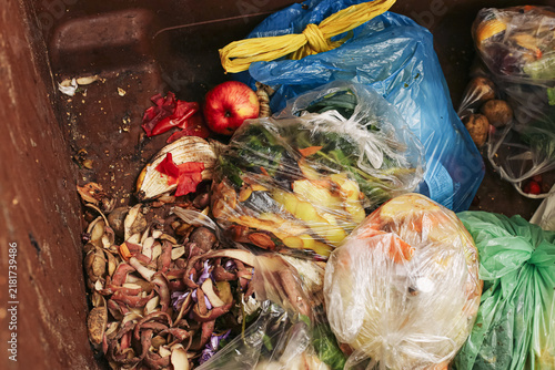 Konstfotografi Discarded vegetables fruit scraps and plastic bags fill a large waste container