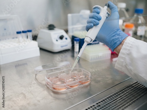 Close up of scientist hand using micropipette to dispense liquid in laboratory