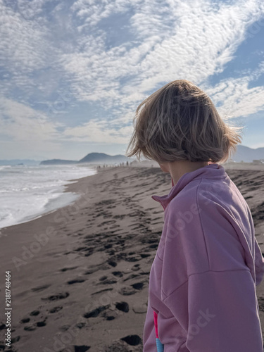 Принти на полотні Woman looks along misty Pacific Ocean coast while standing on black volcanic sand at Khalaktyrsky Beach in Kamchatka