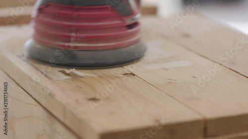 woodworker using an electric orbital sander on a wood project