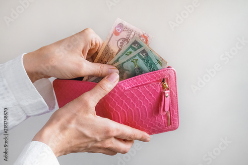 Family budgeting and saving concept with woman taking cash out of a pink wallet