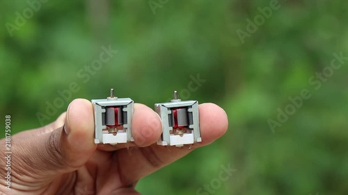Dc motor with single shaft and visible internal parts held in the hand on natural light background