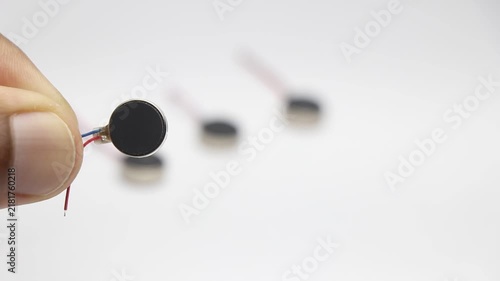 Coin type micro vibration motor held in hand with other motors blurred in background