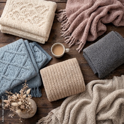 Cozy knitted throws and a warm mug of coffee arranged on a rustic wooden table