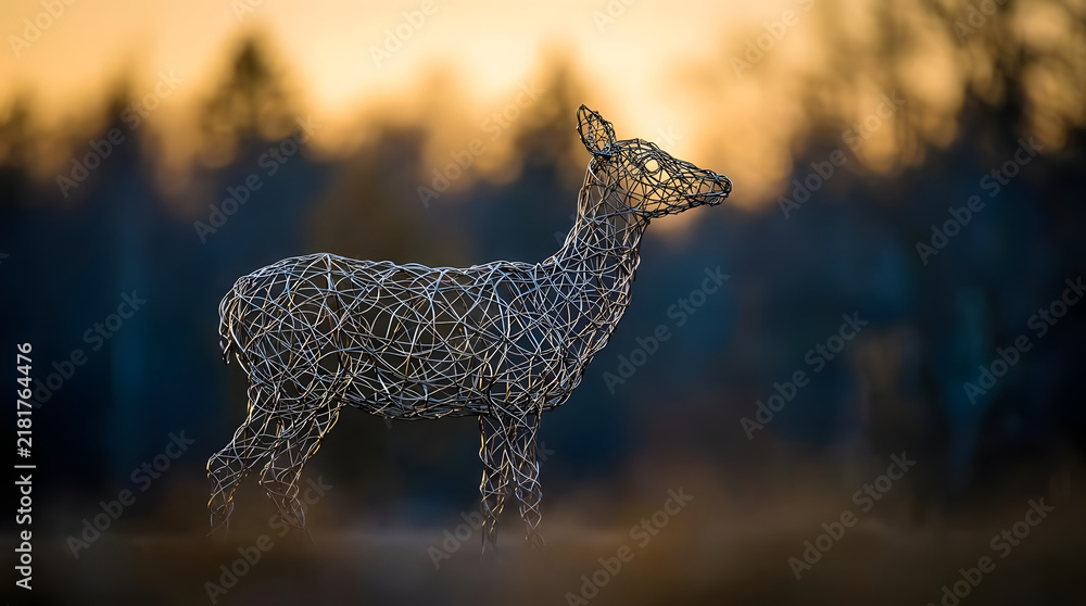 Obraz premium Wire sculpture of deer in forest at golden hour.