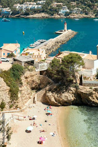 View of the harbor entrance with the breakwater and lighthouse, and a sandy beach in the foreground in Port d’Andratx – 1175