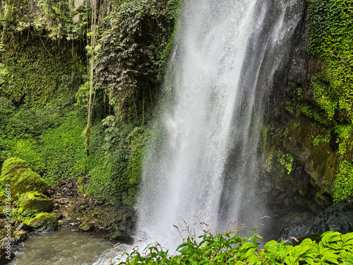 Misty waterfall cascades down mossy cliffside