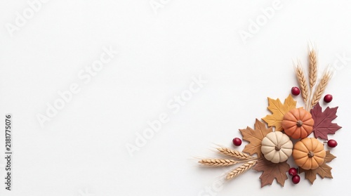 A beautiful festive thanksgiving corner arrangement featuring miniature pumpkins colorful autumn leaves and dried wheat stalks isolated on a clean white background for seasonal design