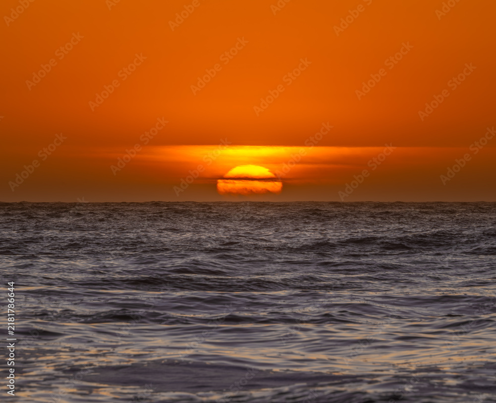 Fototapeta premium Deep Orange Sun Sinks Into The Clouds And Pacific Ocean