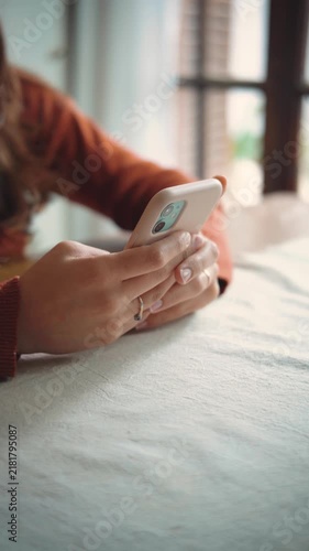 Close-up of an anonymous woman using her smartphone at home, highlighting mobile technology, digital communication, screen time, and everyday domestic life.
