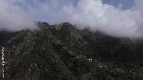 Scenic aerial footage of a mountain village surrounded by a dense forest under a cloudy sky
