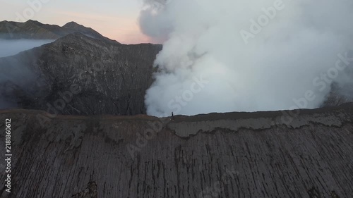 Majestic aerial view of a single person hiking on the edge of the active bromo volcano in indonesia