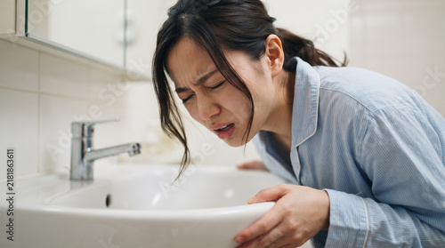 Obraz w ramie 洗面台で吐き気や体調不良に苦しむパジャマ姿の若い女性