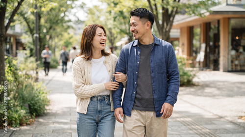 Plakat 腕を組んで街並みを笑顔で歩く若いカップルと夫婦の散歩風景