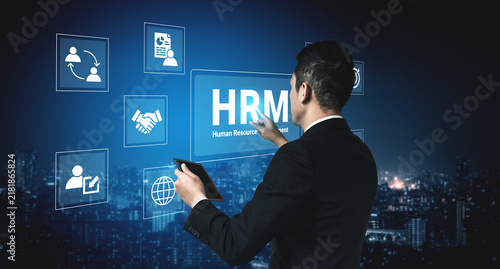 Fotografie A business professional interacts with a human resource management interface in a modern digital environment, showcasing innovation and strategy against a city skyline backdrop