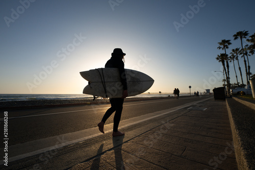 Konstfotografi Surfer Walking with Surfboard Toward the Ocean at Golden Hour on a Palm-Lined Co